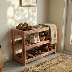 Wooden shoe rack with shoes and a blanket in a well-lit room.